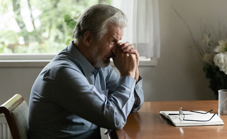 Middle aged man suffering from depression sat at his desk
