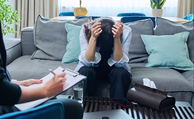 Woman crying during therapy session as psychologist delivers news about her addiction