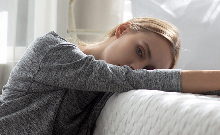 Woman next to bed suffering with symptoms of somatic syndrome