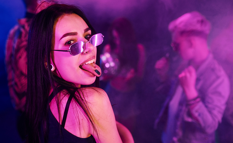 Woman taking ecstasy tablet at a night club and dancing